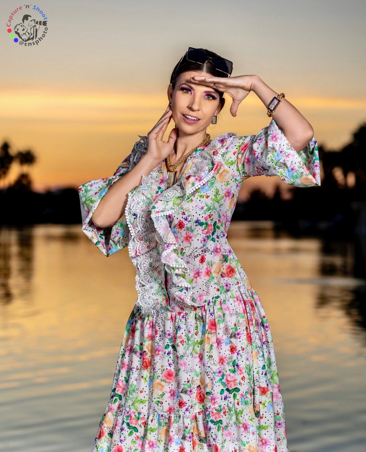 Close up of woman in a couture long sleeve floral dress with front ruffle waterfront at sunset